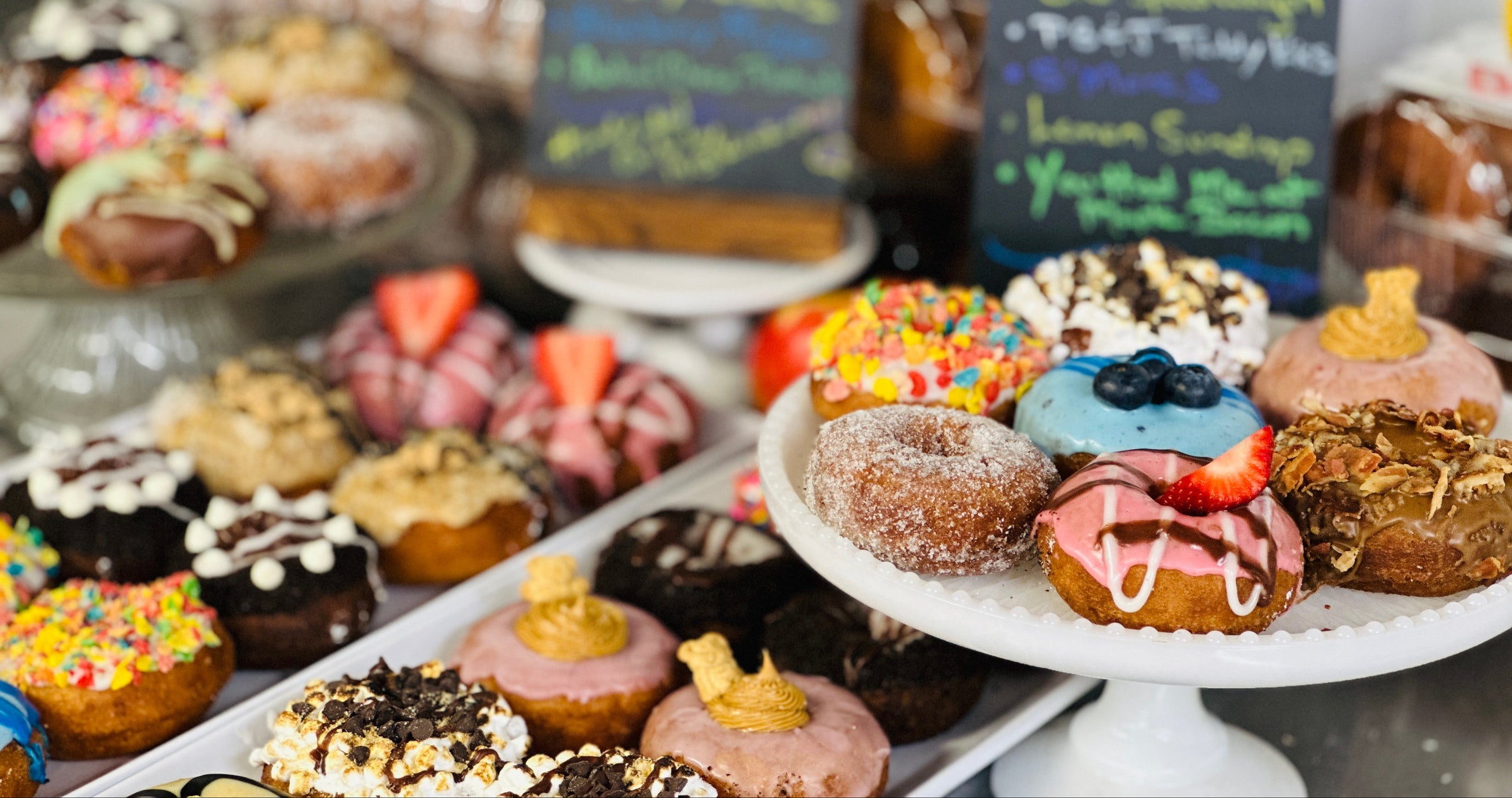 Display of various decorated donuts with signs in the background
